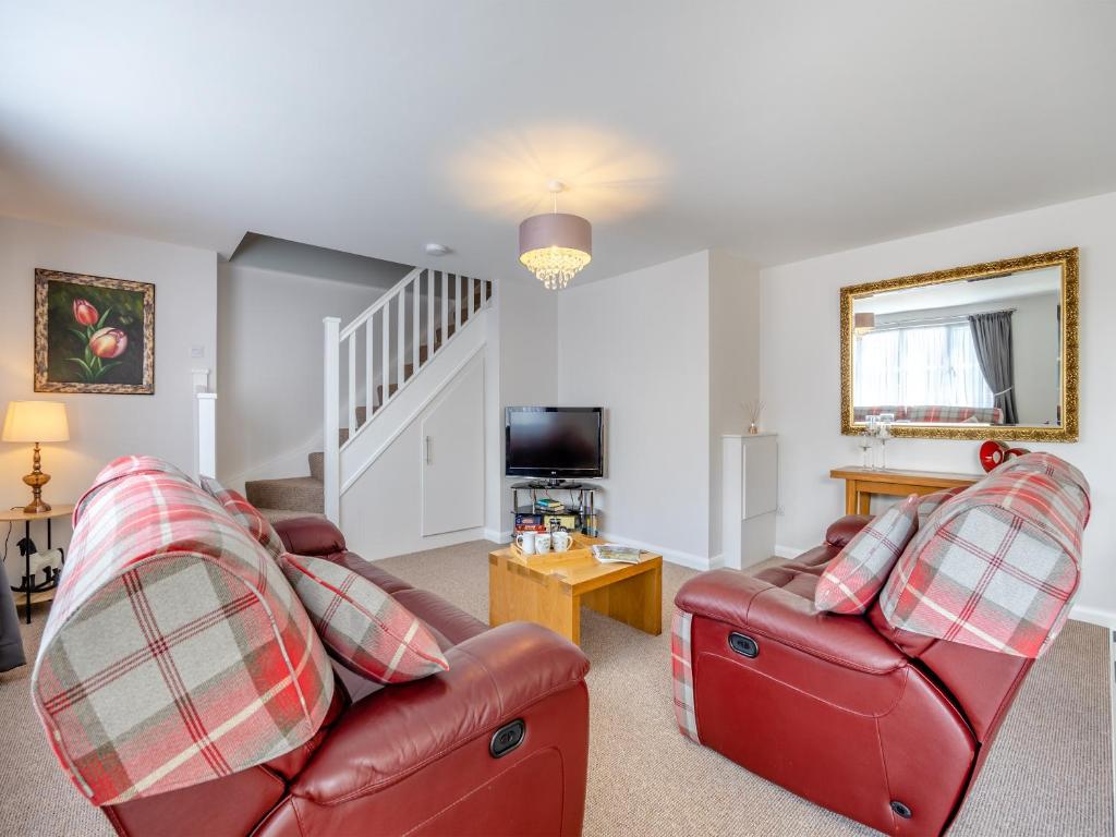 a living room with two red leather couches and a tv at Willows Cottage - Uk42144 in North Somercotes