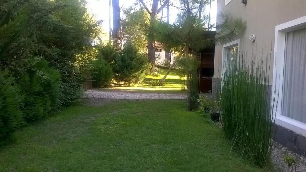 un patio con césped y árboles y una casa en Duplex en Alquiler con Pileta Privada Pinamar Valeria del Mar en Valeria del Mar