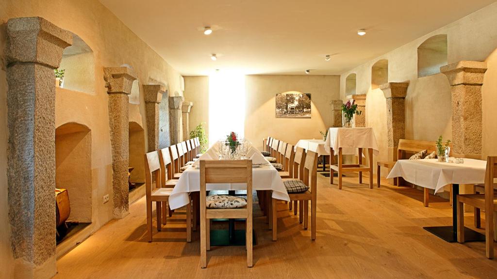 un comedor con mesas y sillas blancas en Naturhotel Gidibauer-Hof en Hauzenberg