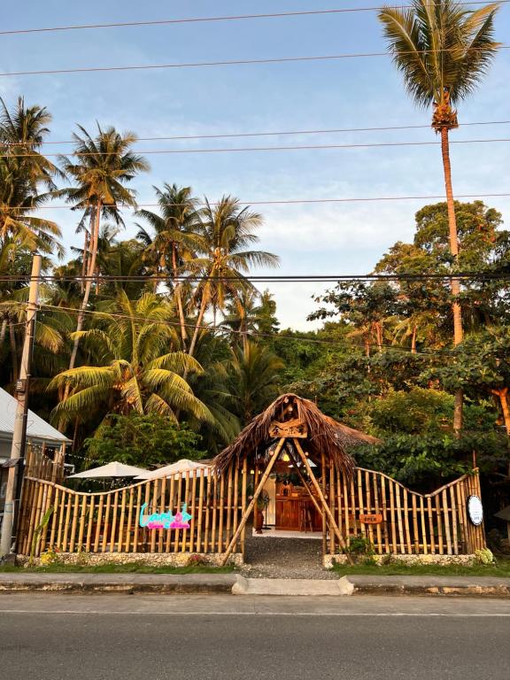 uma pequena casa com uma cerca de madeira e palmeiras em AA Jungle Guesthouse em San Juan