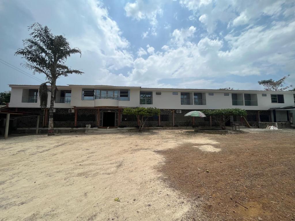 un gran edificio blanco con un árbol delante en Hotel Palmeras Del Sinu, en Lorica