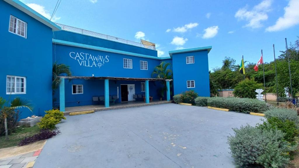 un edificio azul con un aparcamiento enfrente en Castaways Villa, en Duncans