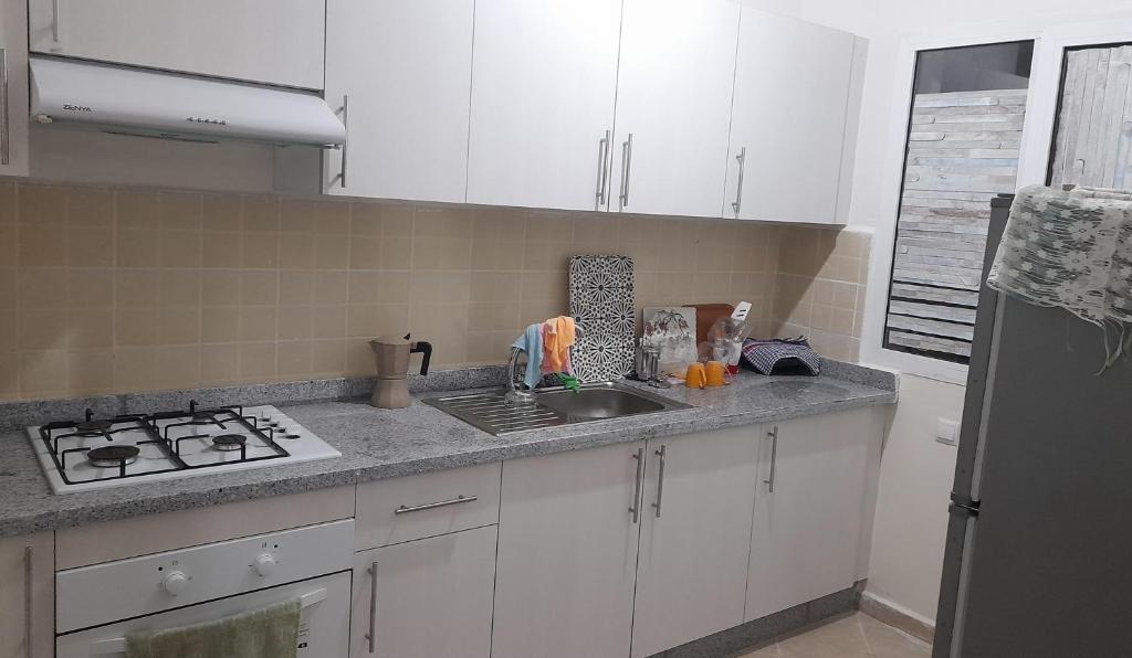 a kitchen with white cabinets and a sink and a stove at استراحتي in Hajreien