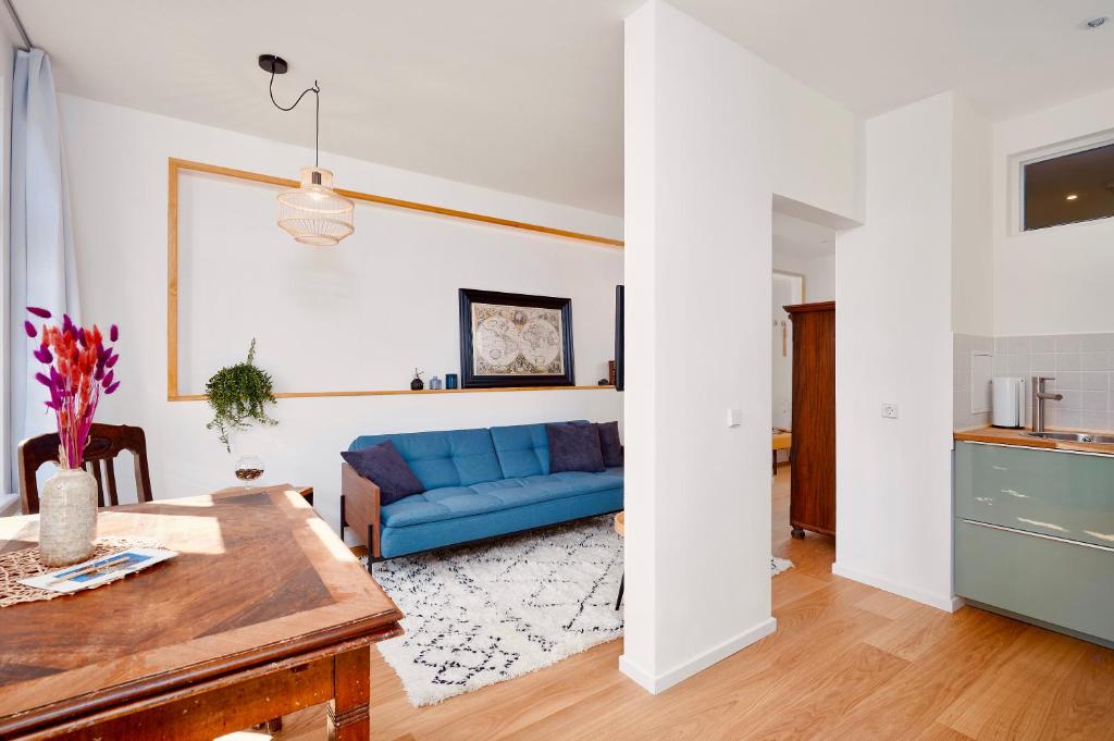 ein Wohnzimmer mit einem blauen Sofa und einem Tisch in der Unterkunft LaMaison Apartment - Ruhige Top-Lage im Zentrum Leipzigs, ideal für Städtereisen & Business in Leipzig