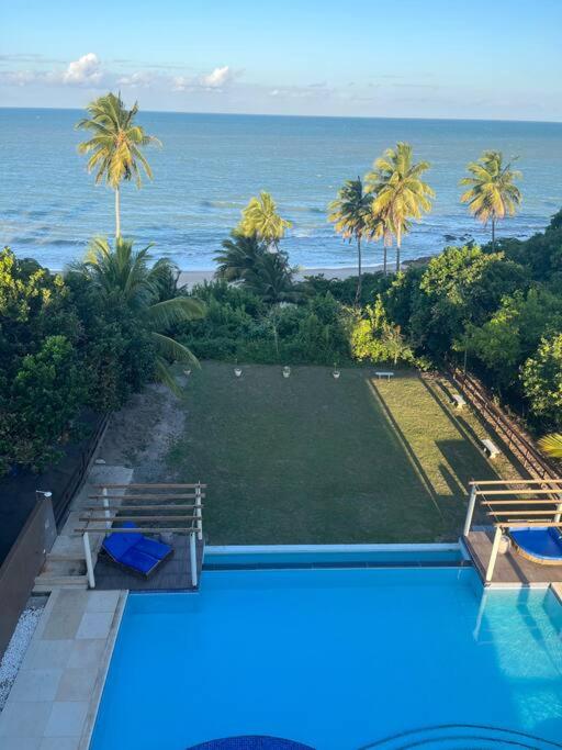 a swimming pool with a view of the ocean at Flat Beira Mar Carapibus in Conde