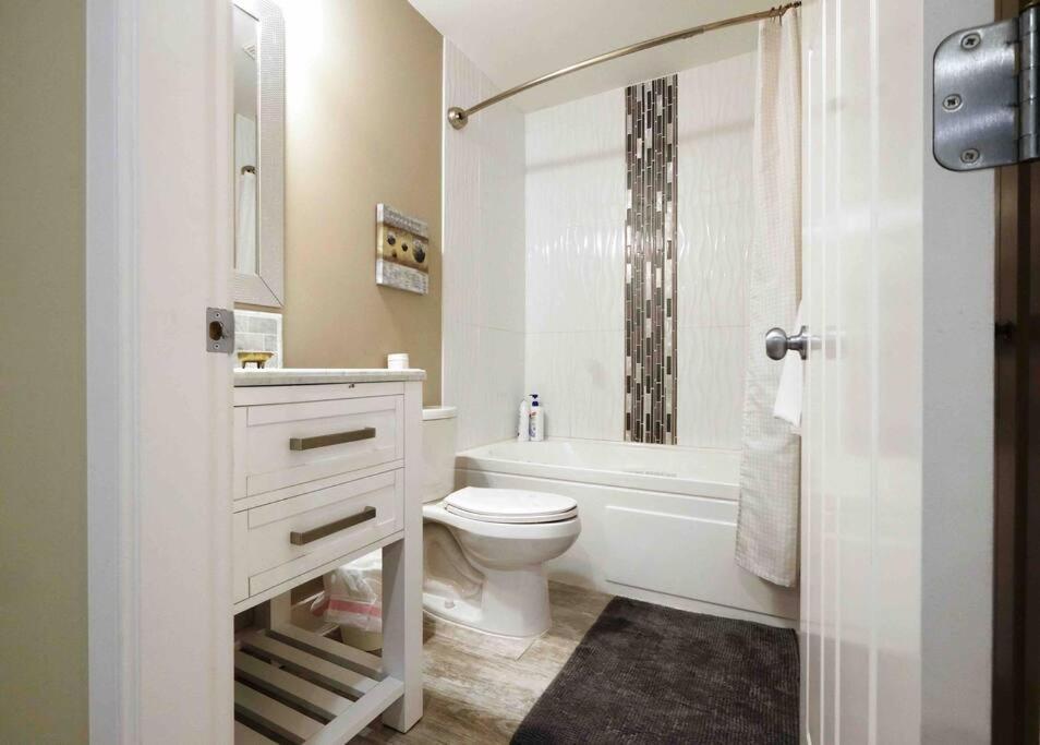 een badkamer met een toilet, een bad en een wastafel bij Cozy Home Nestled in Burke Mountain. in Coquitlam