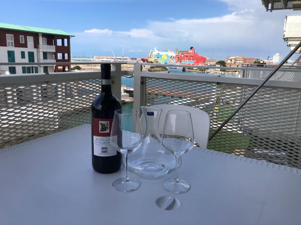 a bottle of wine and two wine glasses on a balcony at Kasia porta sul mare di Livorno Free parking in Livorno