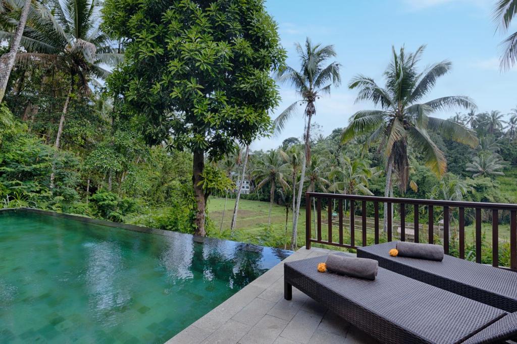 a resort with a swimming pool with two benches at Kelusa Hill in Ubud