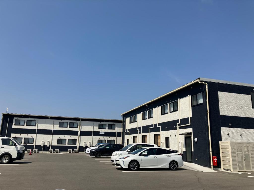 un estacionamiento con autos estacionados frente a un edificio en IMAS Village Court Rokkokuodaka, en Minamisouma