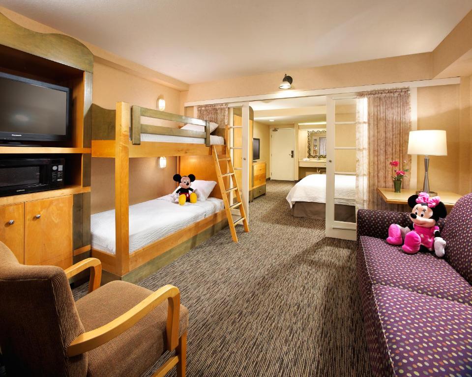 a hotel room with two bunk beds and a couch at Portofino Inn and Suites Anaheim Hotel in Anaheim