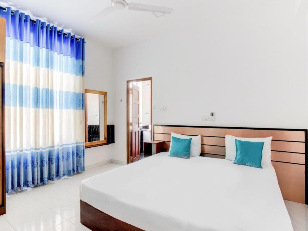 a bedroom with a large white bed with blue pillows at Sycamore Residences in Mount Lavinia