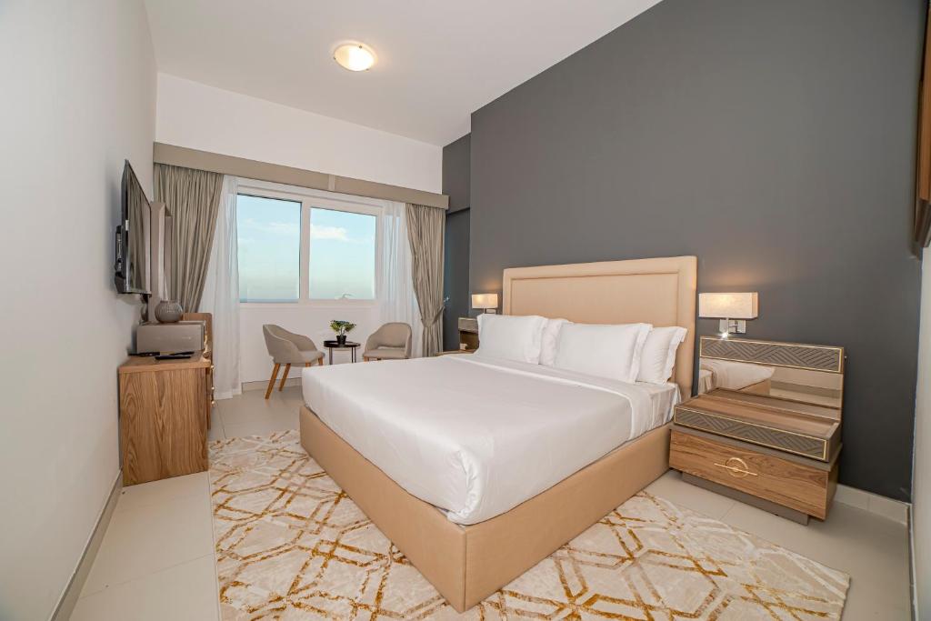 a bedroom with a large white bed and a desk at ABIDOS HOLIDAY HOMES Windsor Residence in Dubai
