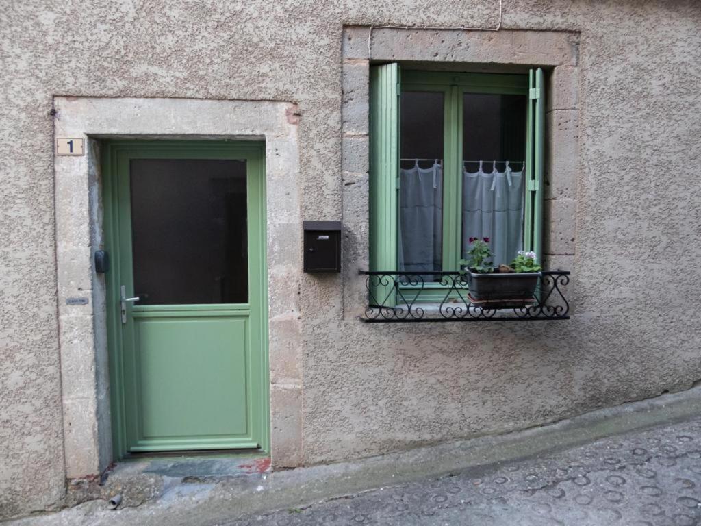a building with a green door and a window with a plant at Maison d’Paula in Avène