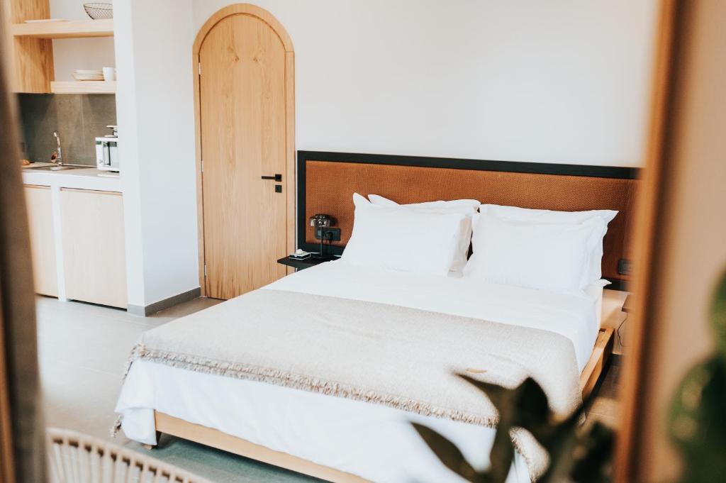 a bedroom with a white bed with a wooden headboard at ANDROMEDA in Kalymnos