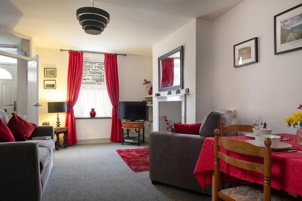 a living room with red curtains and a couch at Miners Cottage in Blaenau-Ffestiniog