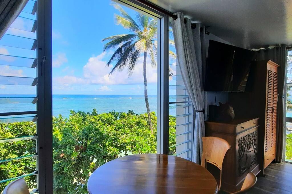 um quarto com uma mesa e vista para o oceano em Breezy Beachfront Bali-Style Haven 180 Degree OceanView em Hauula