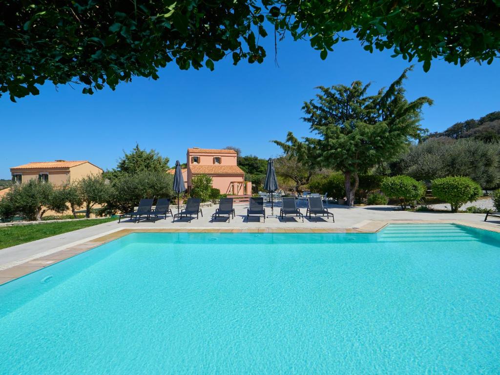 una piscina con sedie e una casa sullo sfondo di Eliathos Residence Houses ad Archanes