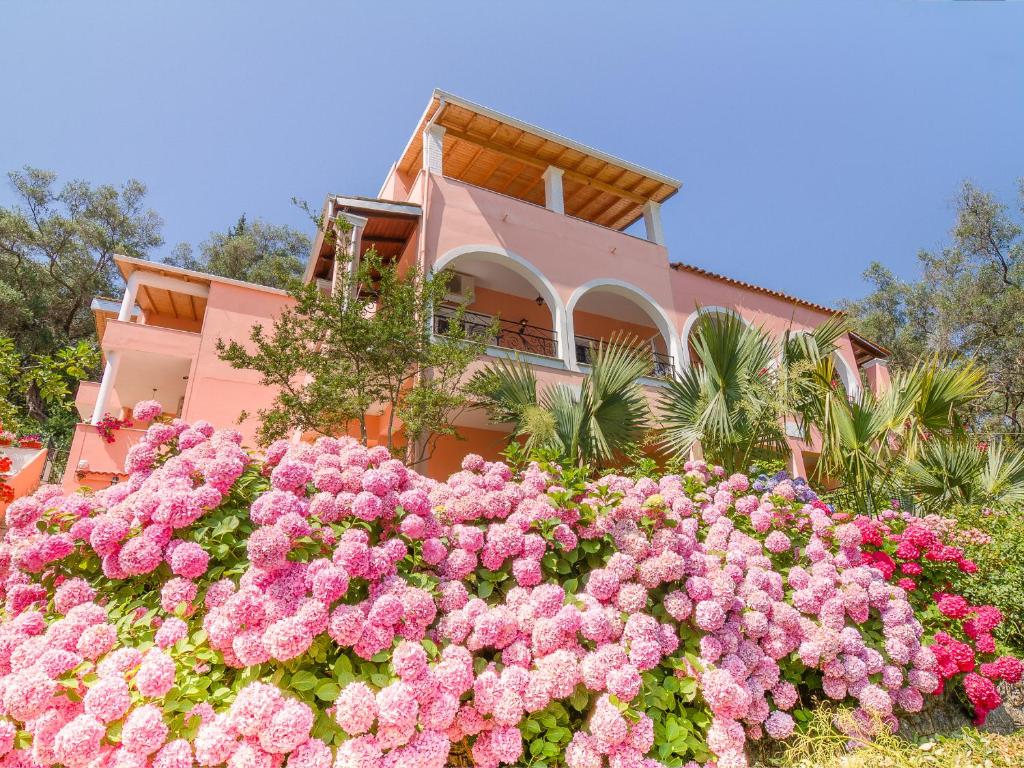 a pink house with a bunch of pink flowers at Evergreen Apartments in Agios Gordios