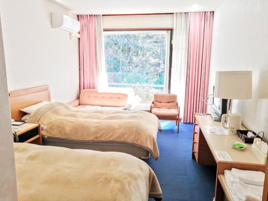 函南町にある南箱根ヴィラのベッド2台と窓が備わるホテルルームです。