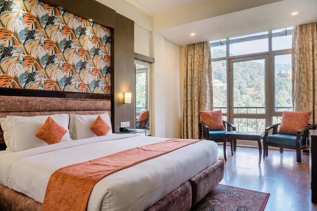 a bedroom with a large bed and a large window at Hotel Shiva Continental in Mussoorie