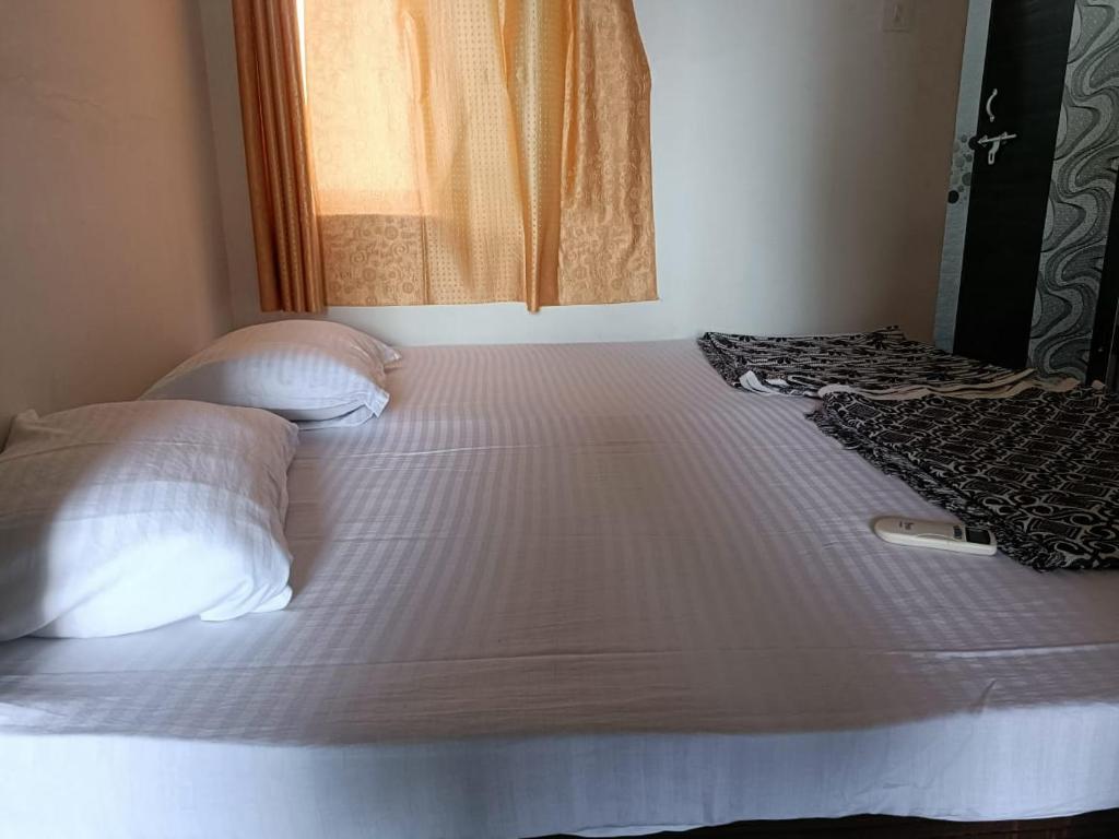 een groot wit bed met 2 kussens en een raam bij ashapura home stay in Navgam