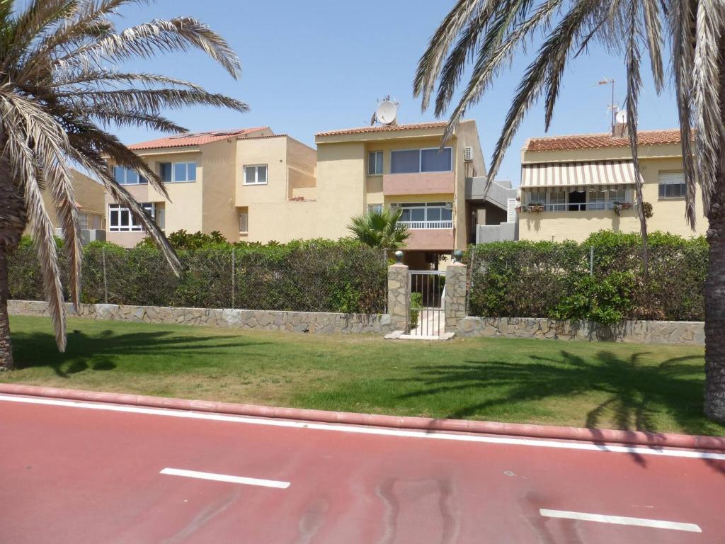 una calle frente a una casa con palmeras en Don Paco - Front Line Of The Beach Apartment en Roquetas de Mar