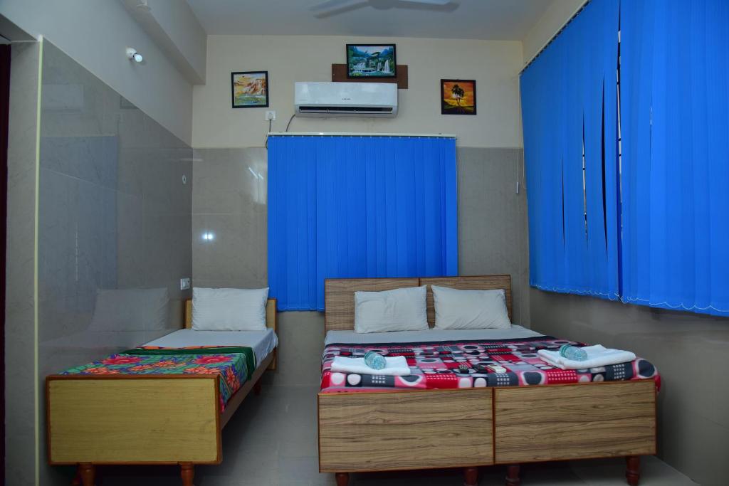 two beds in a room with blue cabinets at SGRT Residency in Vellore