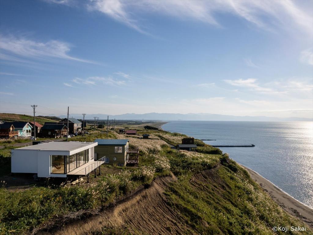 a house on a cliff next to the ocean at Cliff House Morai in Ishikari