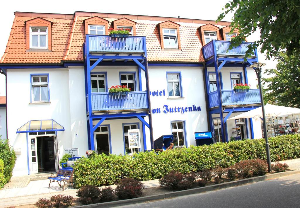 a white building with blue balconies on a street at Hotel von Jutrzenka in Kühlungsborn