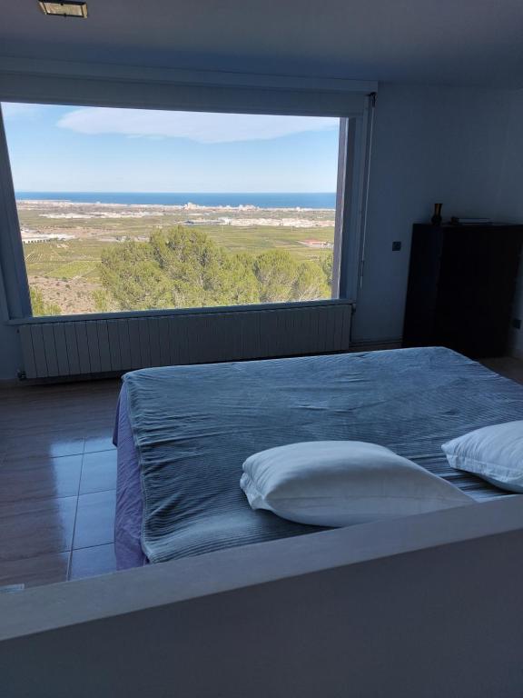 uma cama num quarto com uma grande janela em Tossal Home em Castillo del Reboller