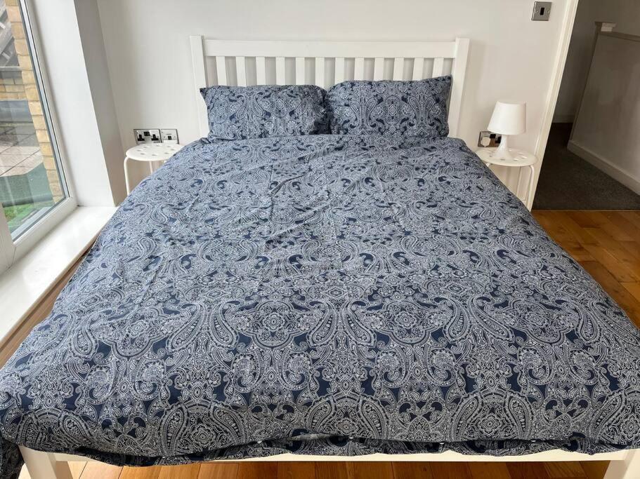 Bett mit blauer Bettdecke und blauen Kissen in der Unterkunft Bluebell Cottage - private coach house, garage & parking in Greenhithe