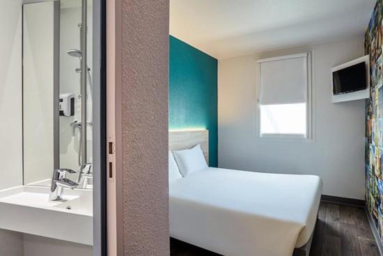 uma casa de banho com uma cama branca e um lavatório. em HOTEL F1 SAINT-LO em Saint-Lô