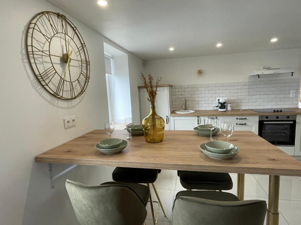 a kitchen with a wooden table with chairs and a clock at Appartement L’opale d’Anaé in Boulogne-sur-Mer