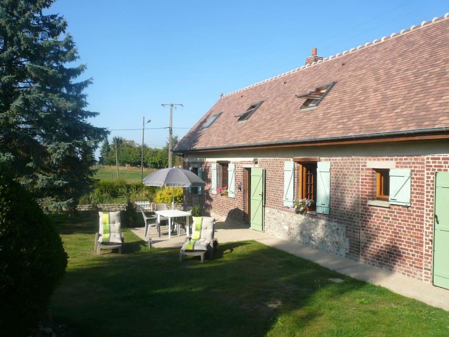 une maison en briques avec une table, des chaises et un parasol dans l'établissement Les hortensias, à Guiseniers