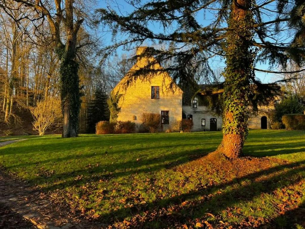 una casa en medio de un campo con un árbol en The Holy Farmhouse, en Fontaine-Simon