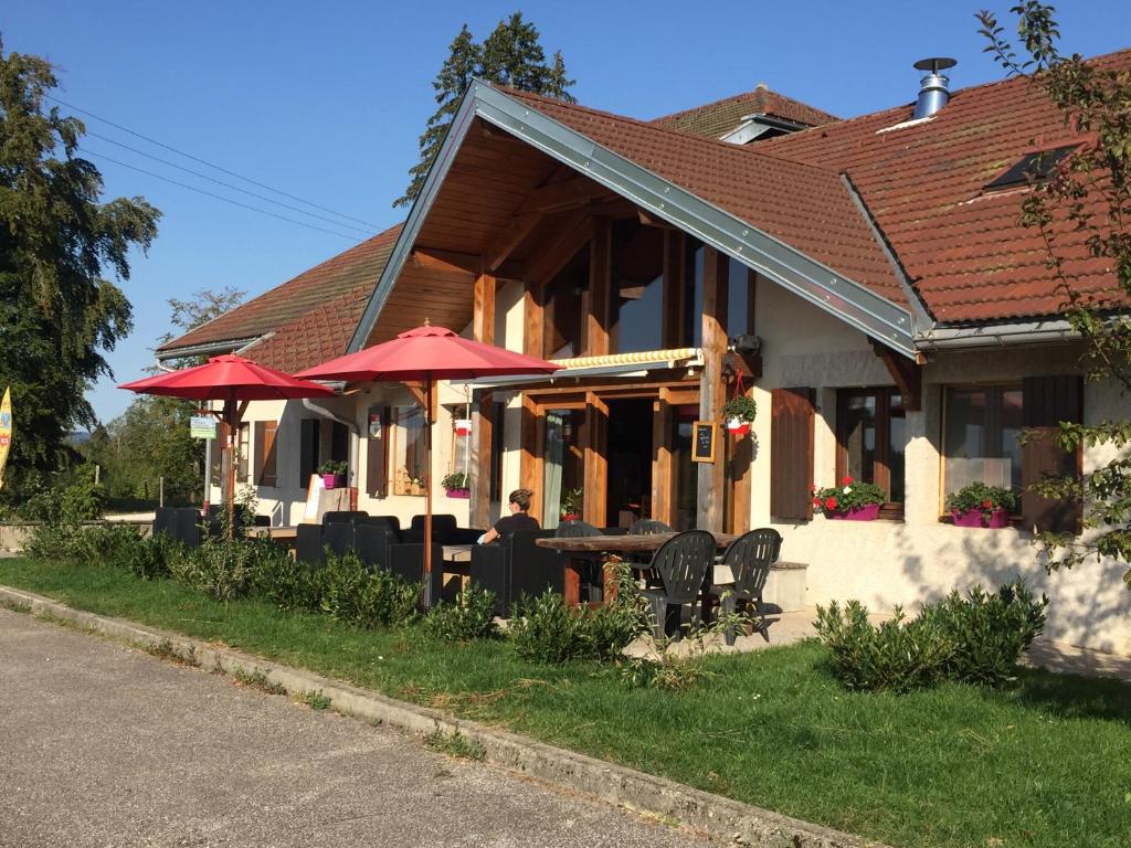 un ristorante con tavoli e ombrelloni di fronte a un edificio di Domaine du Bugnon a Lac des Rouges Truites