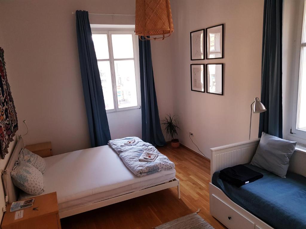 a room with a bed and a couch and windows at be at home with Philip & Marie in Klagenfurt