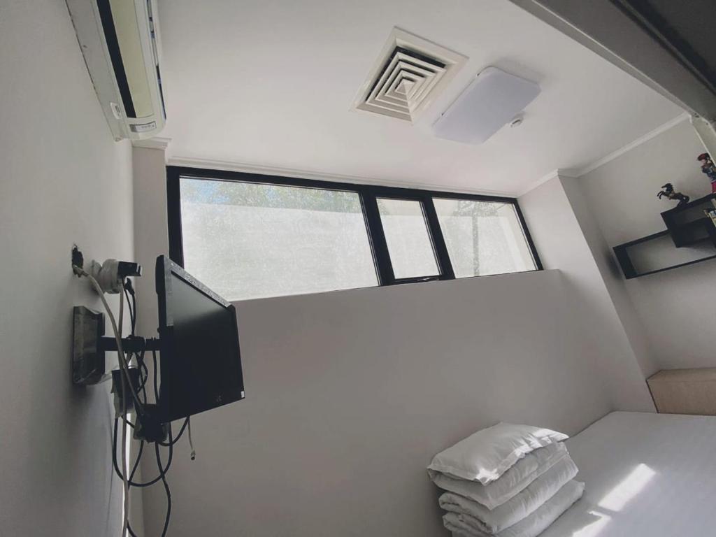 Habitación pequeña con TV y cama con toallas. en Hotel Kapsula en Astaná