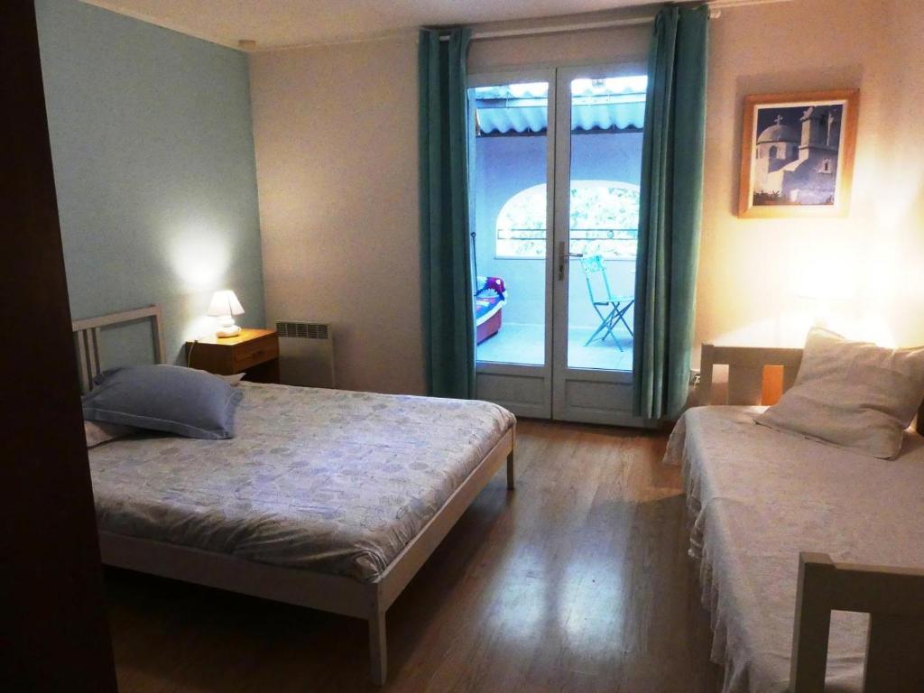 1 dormitorio con 2 camas y puerta a un balcón en L'ancien Cinéma, en Canet d'Aude