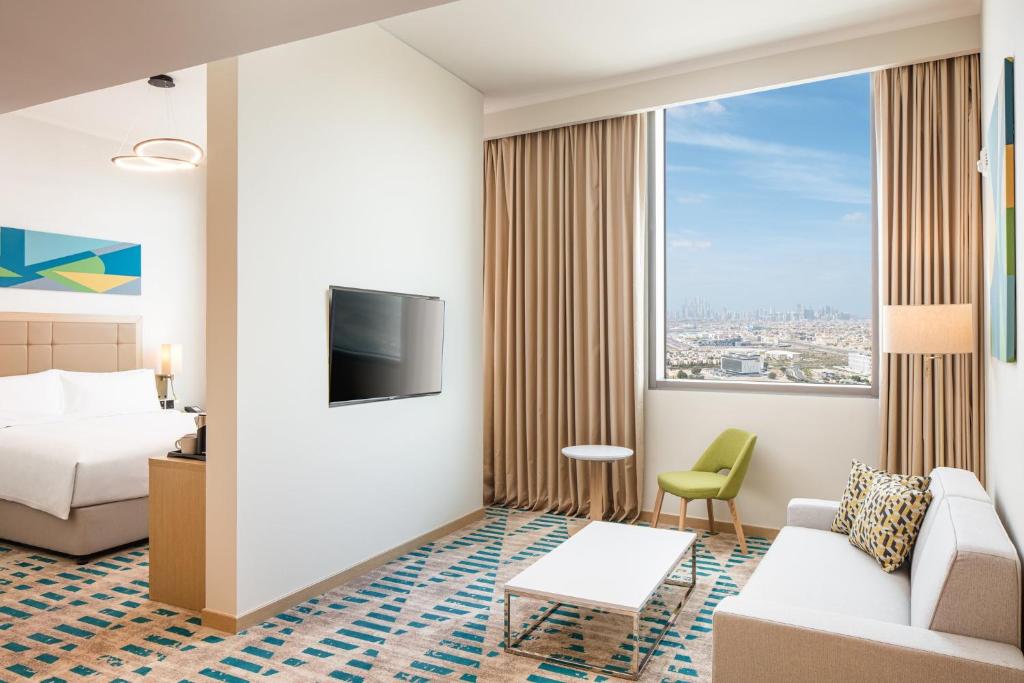 Holiday Inn & Suites - Dubai Science Park, an IHG Hotel في دبي: غرفة فندقية بسرير ونافذة كبيرة