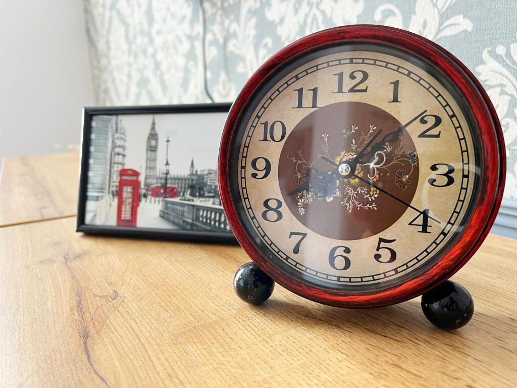 une horloge rouge assise sur une table à côté d'une photo dans l'établissement Apartament Winston, à Szczawno-Zdrój