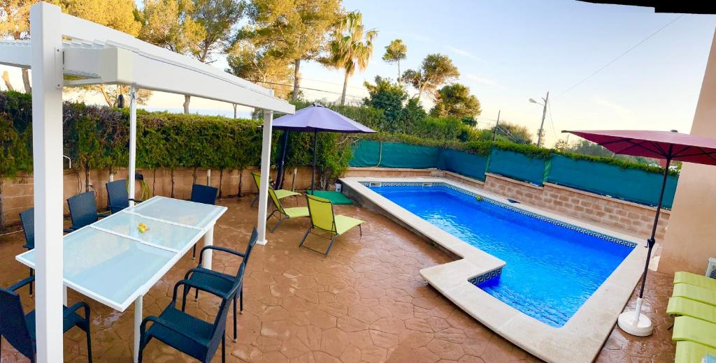 a pool with a table and chairs and an umbrella at Casa Xisca in Cala Pi