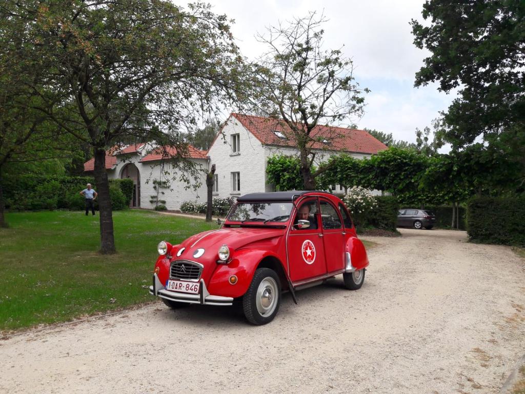 um pequeno carro vermelho estacionado numa estrada de terra batida em Ca'Triz em Borgloon