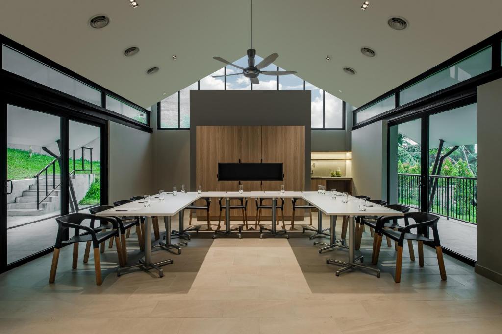 A glass-walled meeting room with flexible table seating and a presentation screen.