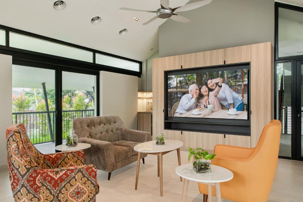 A bright lounge with balcony doors, a large television, sofas, and accent chairs.