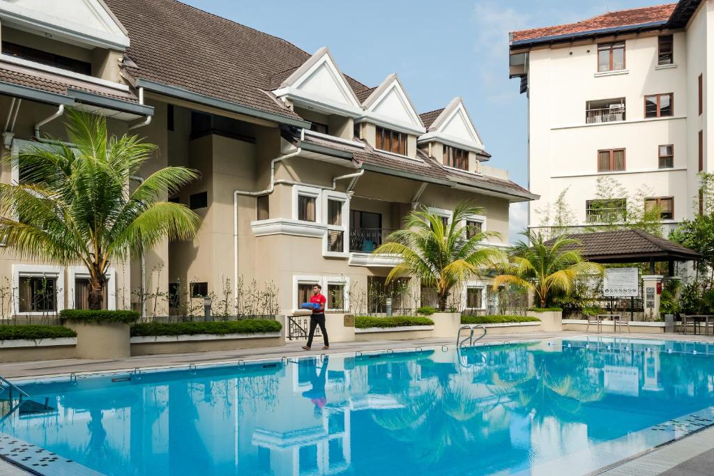 A sunny outdoor pool beside the hotel’s palm-lined residential-style buildings.