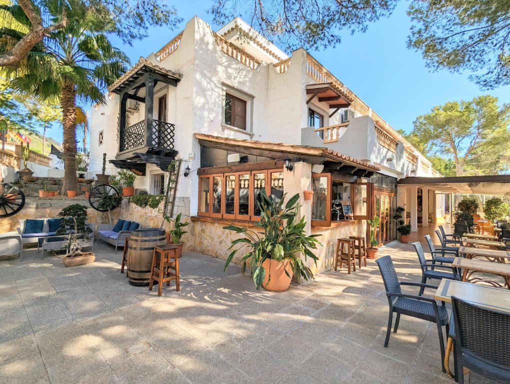 un patio al aire libre con mesas y sillas frente a un edificio en Don Carlos en Paguera