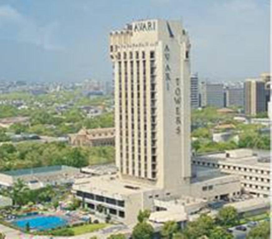 卡拉奇Avari Towers Karachi的一座高大的白色建筑，前面有一个游泳池