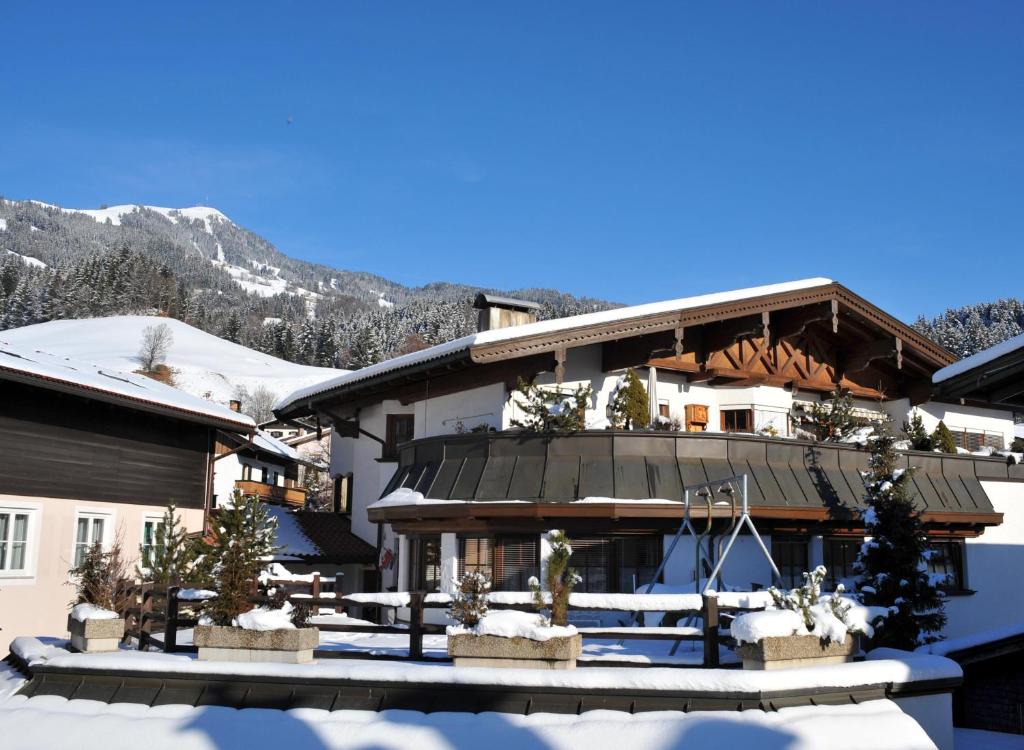 a house in the snow with mountains in the background at Ferienwohnung Kober in Hopfgarten im Brixental
