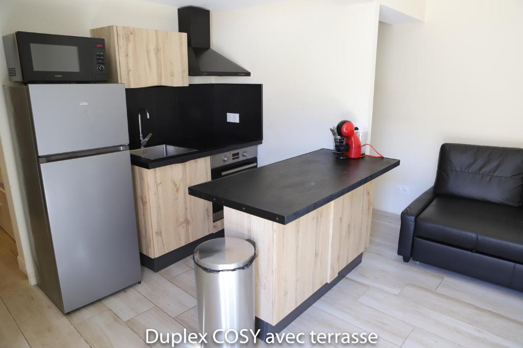a kitchen with a black counter top and a refrigerator at Duplex cosy avec terrasse in Marseille